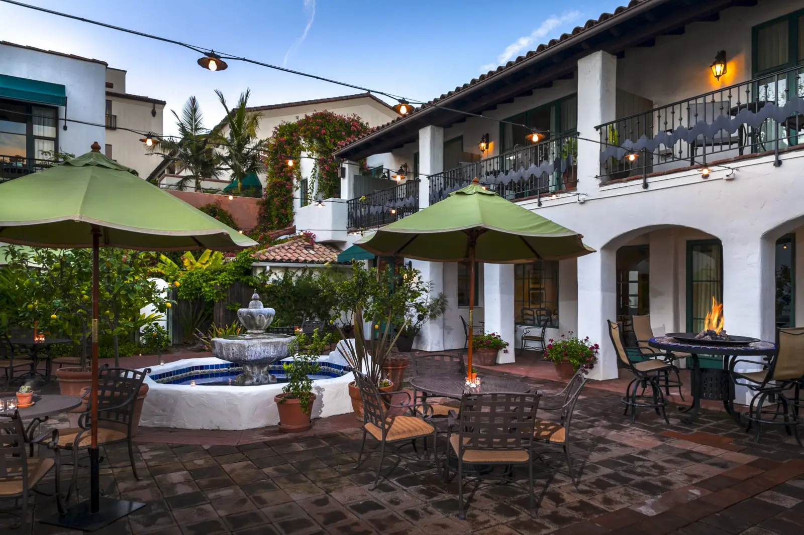 Evening courtyard with a fountain and string lights at a broughtonHOTELS client property